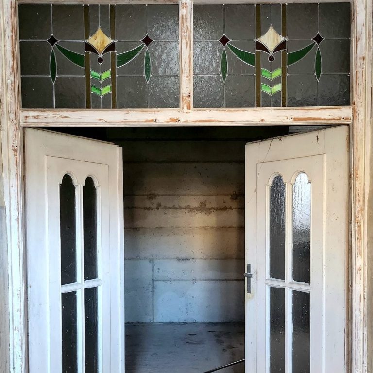 Es ist eine Flügeltür mit Buntglasfenstern im Jugendstil zu sehen. Die Tür verbindet die Galerieräume miteinander.